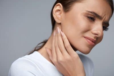 woman holding her jaw in pain